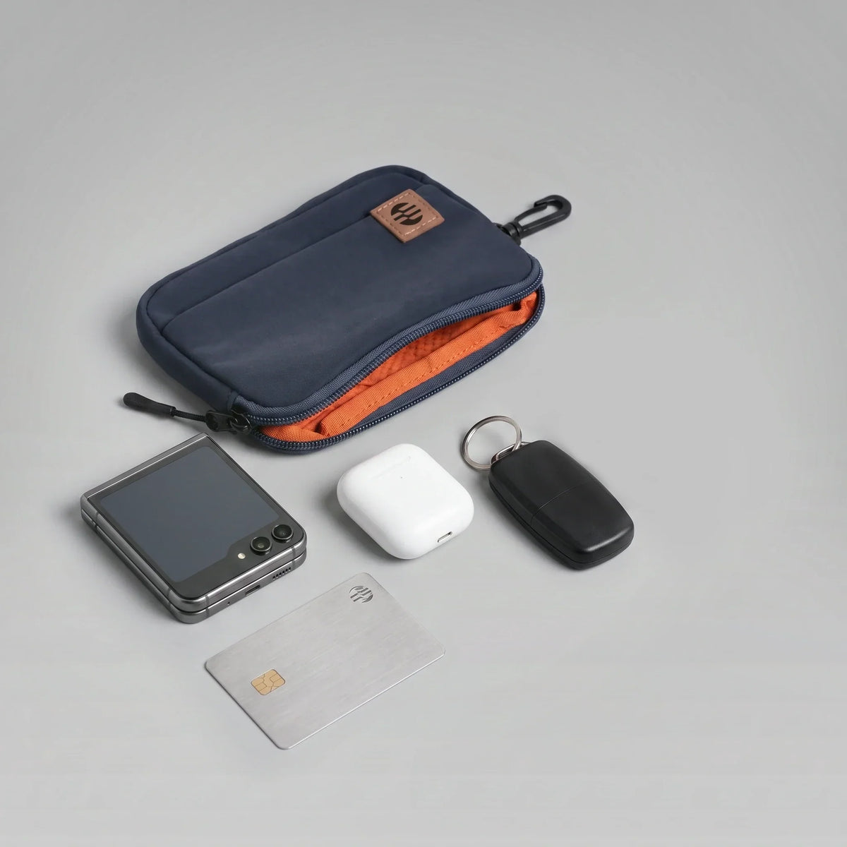 A hybeks Drift Kit in Midnight Transit laid out flat with the phone, earbuds, card and key tracker it holds, the kind of reachable kit a power bank has to travel in at your seat