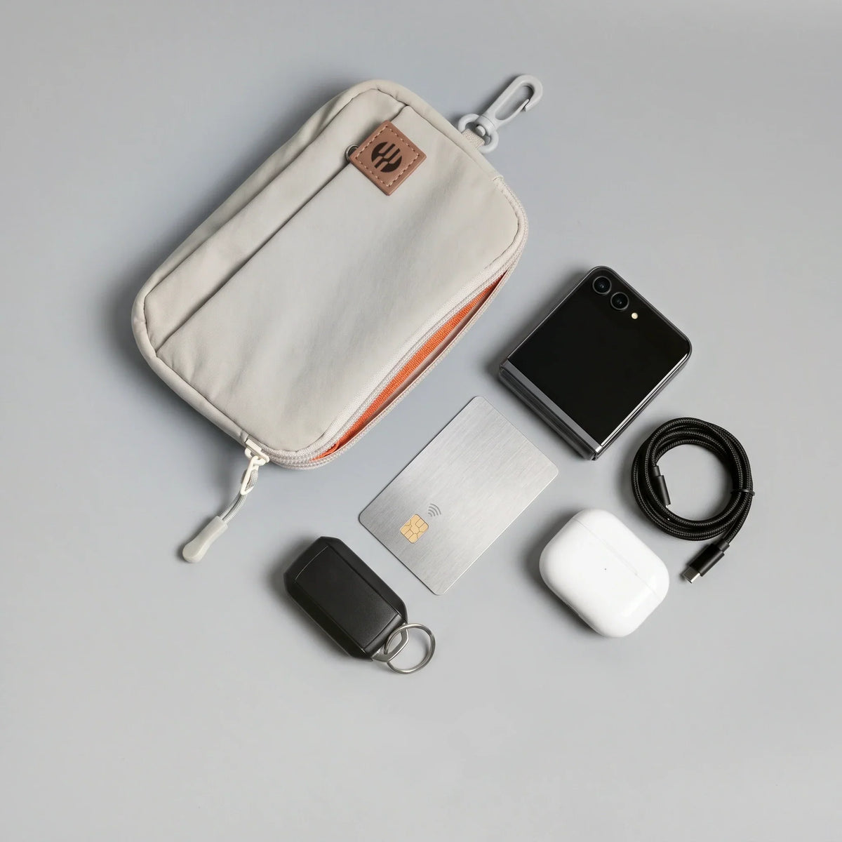 A hybeks Drift Kit in Morning Fog laid out flat with the earbuds, cable, card, phone and key tracker that make up an everyday work bag carry