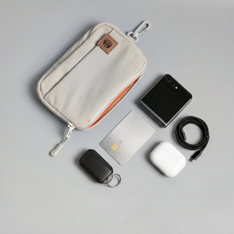 A hybeks Drift Kit in Morning Fog laid out flat with the earbuds, cable, card, phone and key tracker that make up an everyday work bag carry