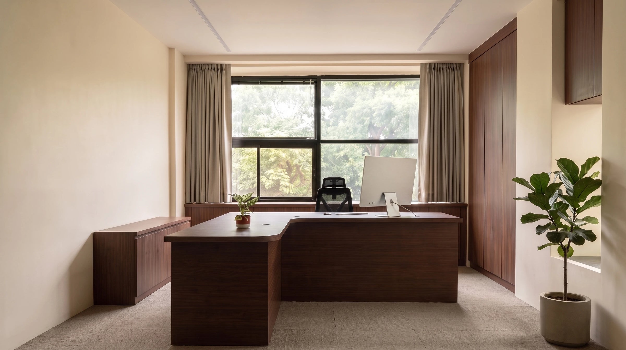 The hybeks studio office, with a dark timber desk set against a window looking onto trees.